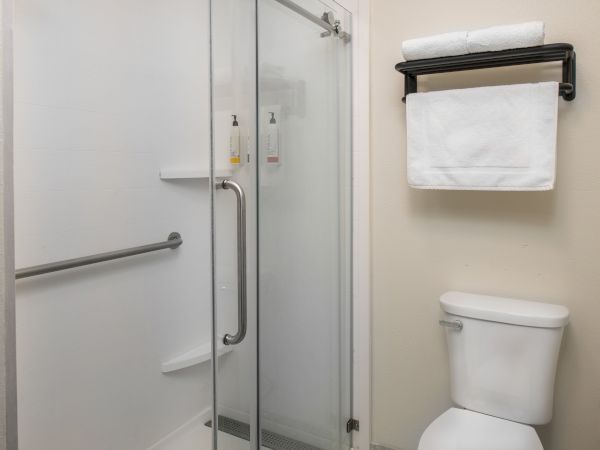 A modern bathroom with a glass shower door, towel rack above the toilet, and a white toilet&mdash;clean and minimal.