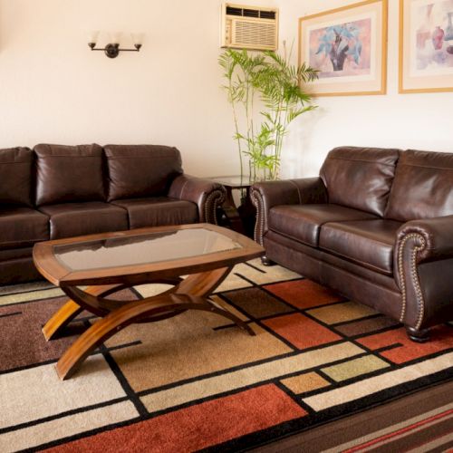 A cozy living room with a dark sofa, colorful rug, and framed art on light walls, creating a warm, inviting space.