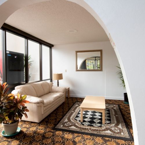 A cozy living room with a large wooden sofa, warm lighting, plants, and artwork; inviting, rustic-modern decor.
