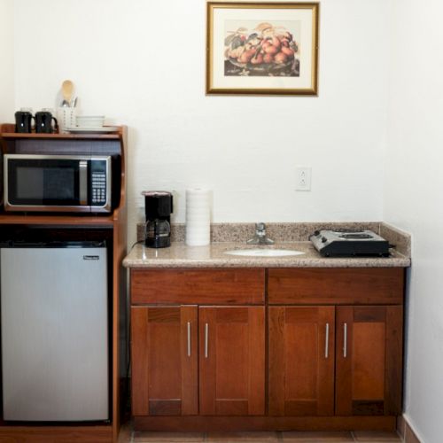 A vintage living room setup with a wooden cabinet, a small CRT TV on the left, a shelf with items, and framed pictures on the wall.