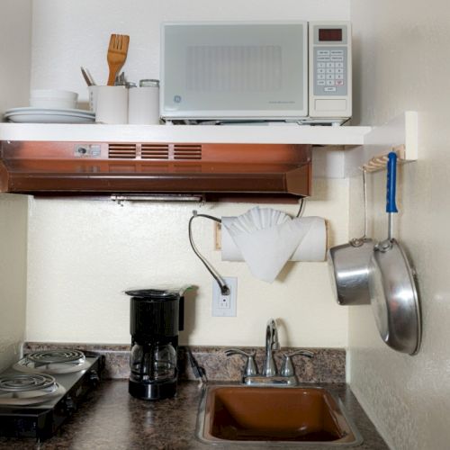 A wall-mounted air conditioner above a wooden desk with a small chair and laptop; cozy home office setup. End with a period.