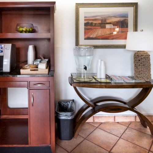 A tidy meditation corner in a cozy room with a low table, cushions, plants, a window, and framed artwork creating a calm, inviting vibe.
