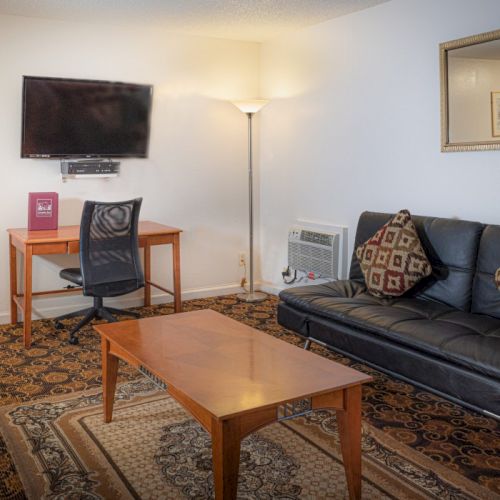 A cozy living room with a striped sofa, wooden coffee table, a small lamp, framed art, and a warm, inviting vibe.