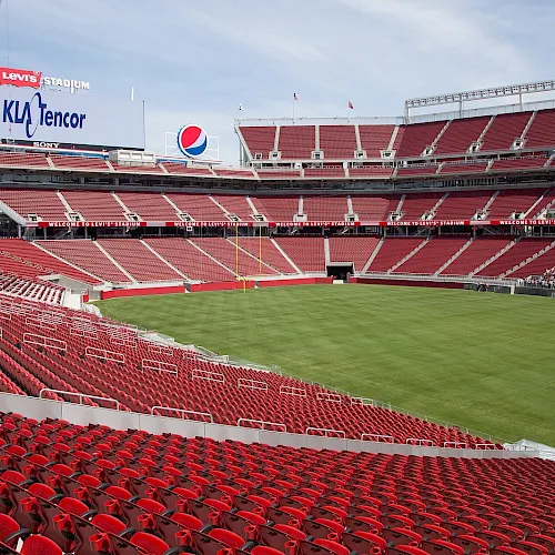 Levi’s Stadium packed with red seats and a green field, with big screens and signs above on match day.
